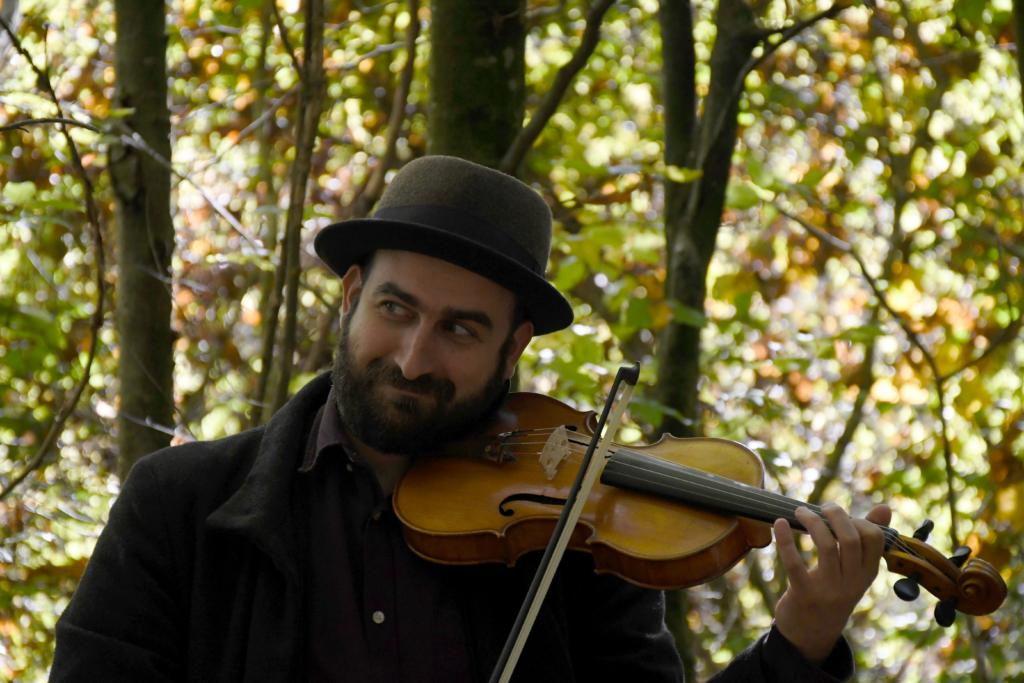 Porträtaufnahme von Larsen, der im Wald Geige spielt, Originalgrösse