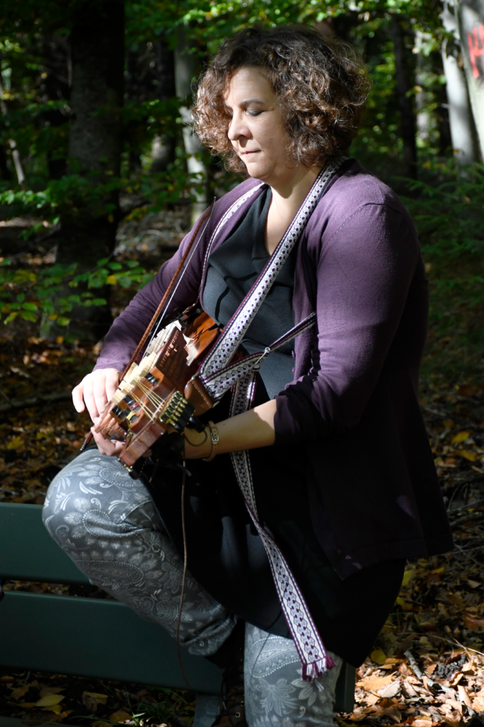 Nahaufnahme von Elena, die im Wald Nyckelharpa spielt, Originalgrösse
