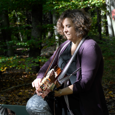 Nahaufnahme von Elena, die im Wald Nyckelharpa spielt
